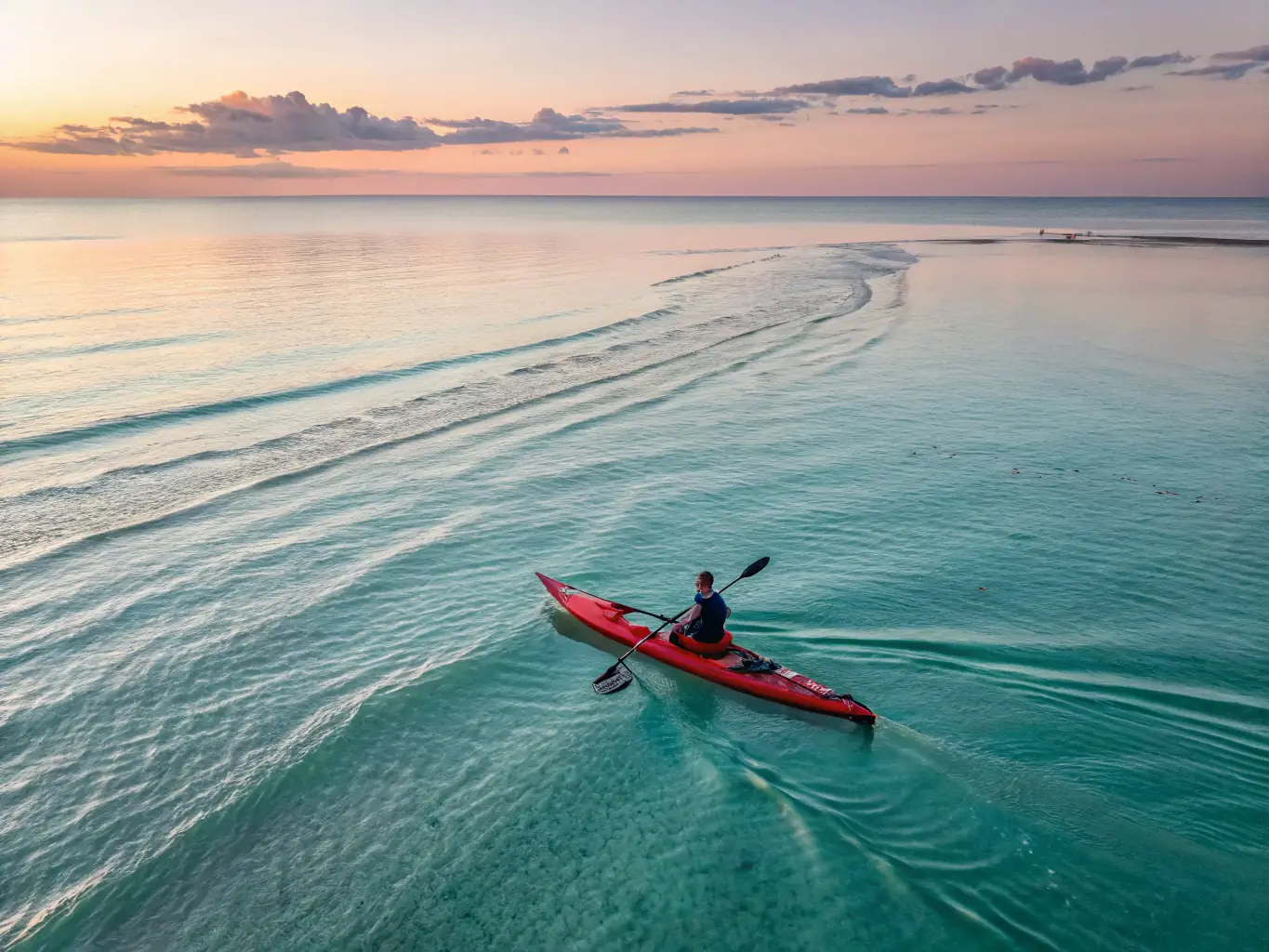 A serene image of a kayaker peacefully paddling through calm, turquoise waters at sunrise, reflecting the tranquility and beauty of the ocean.
